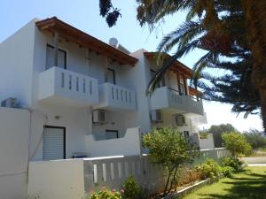 a white house with a white fence and trees at Nikos Apartments & Studios in Plakias