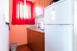 a kitchen with a white refrigerator and red curtains at Apartments Sime in Lopar