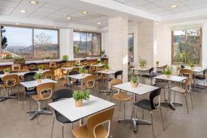 - une salle à manger avec des tables, des chaises et des fenêtres dans l'établissement Metulla Travel Hotel, à Metulla
