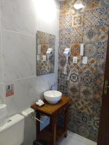 uma casa de banho com lavatório, WC e azulejos em Corrente Marítima Pousada em Fernando de Noronha