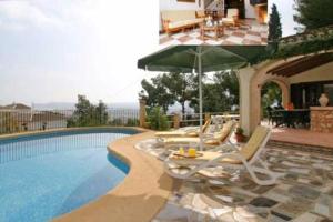 a group of chairs and an umbrella next to a swimming pool at Holiday Home Bonestar in Jávea