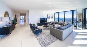 uma sala de estar com um sofá e cadeiras e uma televisão em Melbourne City Apartments Panoramic Skyview Penthouse em Melbourne