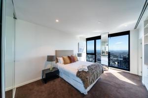 a bedroom with a bed and large windows at Melbourne City Apartments Panoramic Skyview Penthouse in Melbourne