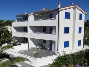 un gran edificio blanco con persianas azules en Apartment Goran - 30m close to the beach, en Verunić