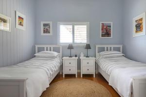 two beds in a white room with a window at Thirlestane Farm Cottage & Barn in Cooroy
