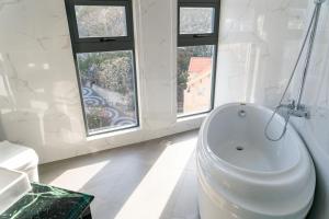 a white bathroom with a tub and windows at Sun Hill Hotel in Vung Tau