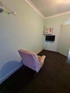 
a small room with a chair and a refrigerator at Manuka Cottage in Broken Hill
