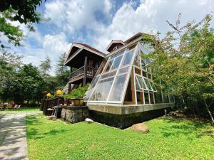 a house with a glass greenhouse on the lawn at Ailiga Travel Villa in Renai