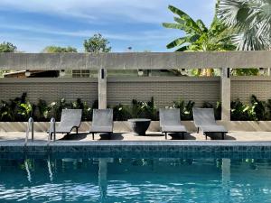 a swimming pool with four chairs next to a fence at Garden Paradise in North Pattaya