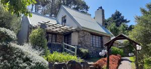 a stone house with a pergola in a garden at Houtkapperspoort Mountain Cottages in Cape Town