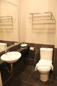 a bathroom with a toilet, sink, and mirror at Seemsoon Hotel in Ipoh