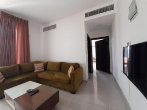 a living room with a couch and a tv at Furnished Apartments Near McDonald's Al-Madina Al-Monawara St in Amman