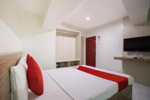 OYO 675 Circuit Hostel في مانيلا: غرفة نوم بسرير ومخدات حمراء وتلفزيون