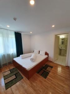 - une chambre avec un lit doté de draps et d'oreillers blancs dans l'établissement Vila IZVORUL MINUNILOR, à Stâna de Vale