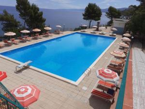 una grande piscina blu con sedie e ombrelloni di Camping & Village Rais Gerbi a Pollina