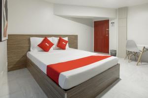 OYO 675 Circuit Hostel في مانيلا: غرفة نوم بسرير كبير ومخدات حمراء