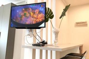 a television on a table with a vase and a plant at ZY Studio @ EVO SOHO Bangi [ASTRO WiFi NETFLIX] in Bangi