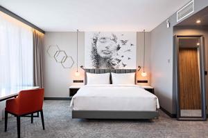 فندق راديسون بلو داوغافا، ريغا في ريغا: غرفة نوم بسرير ابيض كبير وكرسي احمر