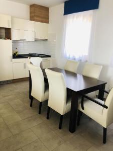 バラトンフレドにあるJacht Apartmanokのキッチン(黒いテーブル、白い椅子付)