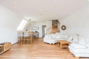 ein Wohnzimmer mit weißen Möbeln und Holzboden in der Unterkunft Ferienhaus Boje 9 in Neuharlingersiel