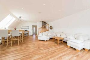 a living room with white couches and a table at Ferienhaus Boje 9 in Neuharlingersiel