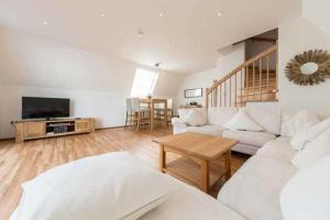 a living room with a white couch and a tv at Ferienhaus Boje 9 in Neuharlingersiel