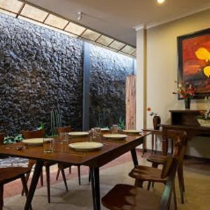 a dining room with a wooden table and chairs at Helena Guest House in Rampal