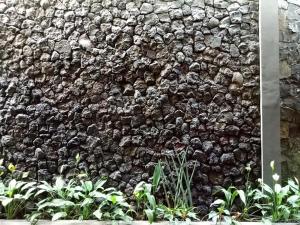 a stone wall with plants in front of it at Helena Guest House in Rampal