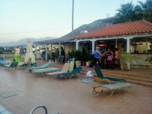 a group of lounge chairs and umbrellas on a patio at Frida Village in Hersonissos