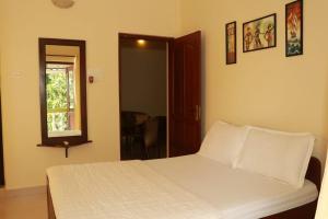 a bedroom with a white bed and a mirror at Peter’s vacation rentals Goa in Calangute
