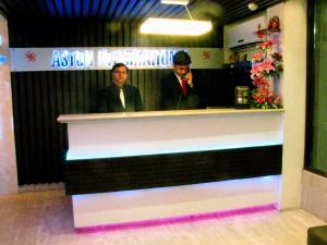two men standing behind a counter in a restaurant at Hotel Aston International in Kolkata