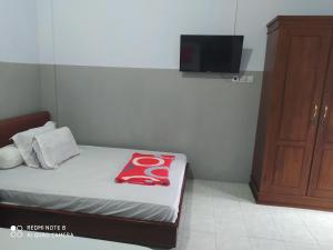 a small bedroom with a bed and a tv at Omah Kost Family Syariah in Tulungagung