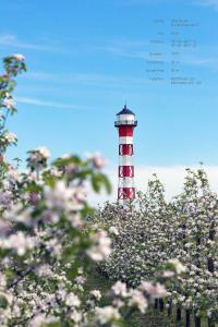 a red and white lighthouse in the middle of flowers at Ferienwohnung Rudis Obstgarten in Jork