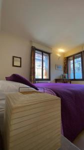 sypialnia z łóżkiem z fioletową pościelą i oknami w obiekcie ARTISTICO - Artistic flat in front of GUGGENHEIM COLLECTION w Wenecji