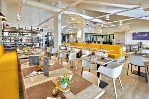 un restaurante con mesas, sillas y cabinas amarillas en ibis budget La Roche Sur Yon Vendespace, en Mouilleron-le-Captif