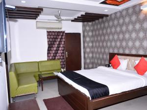 a bedroom with a bed and a green chair at Hotel Flora Inn in Gurgaon