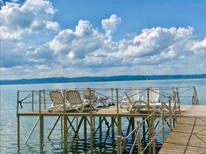 a dock with chairs and a man sitting on it at Residence Hotel Balaton in Siófok