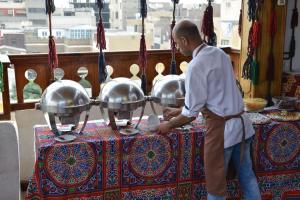 un homme debout devant une table avec trois pots argentés dans l'établissement Nefertiti Hotel Luxor, à Louxor