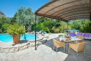 un patio con mesa, sillas y piscina en Owl Booking Villa Rafals - Wonder in the Midst of Nature, en Pollensa