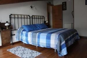 1 dormitorio con 1 cama con manta azul y blanca en Vivienda Vacacional La Casina de Tina - Casas de los Picos, en Mier