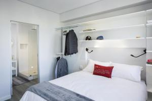 1 dormitorio con cama blanca y almohada roja en 106 On Adderley Accommodation en Ciudad del Cabo