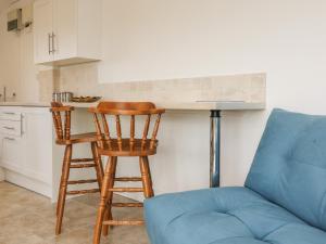 a living room with a blue couch and a kitchen at The Stables in Taunton