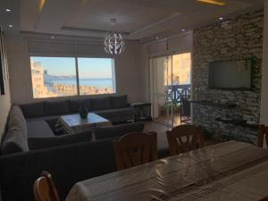 Una sala de estar con un sofá y un televisor. en Duplex vu sur mer, en Martil