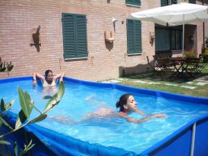 2 personas nadando en una gran piscina en Villa Righino, en Murlo