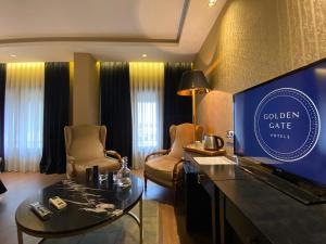 uma sala de estar com uma televisão e um sofá e cadeiras em Golden Gate Hotel Topkapı em Istambul