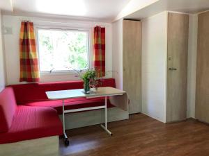 a living room with a red couch and a window at Camping La Bernede in Rennes-les-Bains