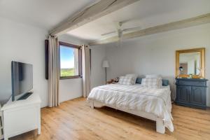 een witte slaapkamer met een bed en een televisie bij Fleur de Lys in Fayence