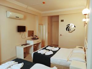 a hotel room with two beds and a television at Aquila Beach Hotel in Fethiye