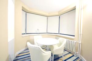 Habitación con sillas blancas, mesa y ventanas. en Grand Nora Hotel en Ankara