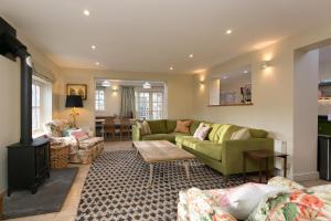 uma sala de estar com sofás verdes e uma lareira em Stunning 3-Bed House in a private hidden valley em Denbigh